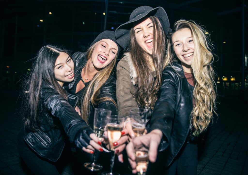 4 meiden met een glas champagne hebben lol tijdens het stappen