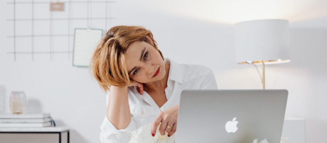 Vrouw kampend met bore-out staart verveelt naar haar MacBook.