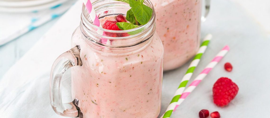 Groot glas met frambozen smoothie en blaadje munt
