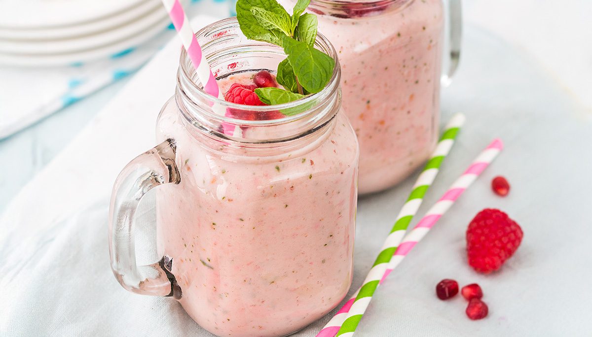 Groot glas met frambozen smoothie en blaadje munt