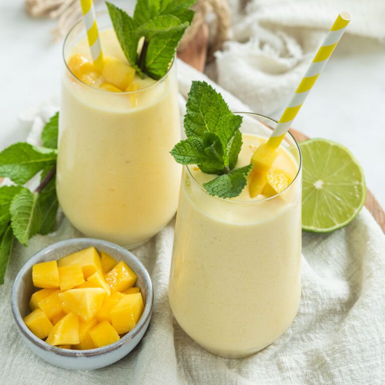 Glas gevuld met smoothie van mango en kokosyoghurt